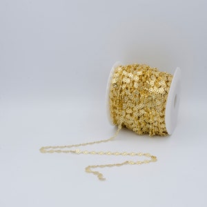 May include: A spool of gold-colored chain with a repeating circular design. The chain is unspooled, revealing the intricate pattern. The chain is made of a shiny, metallic material, perfect for jewelry making or craft projects.