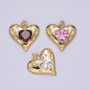 Puede incluir: Tres colgantes de corazón de oro con piedras preciosas de diferentes colores. Los colgantes tienen una superficie texturizada y están decorados con pequeños diamantes de imitación transparentes.