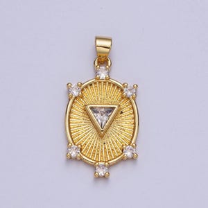 May include: A gold pendant with a circular design featuring a central triangle with a clear stone and surrounded by smaller clear stones.