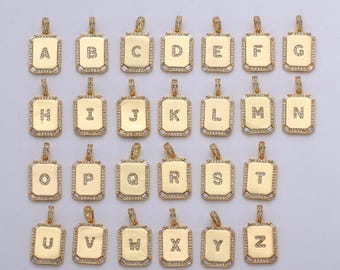May include: A set of 26 gold-tone pendants, each featuring a different letter of the alphabet, set with clear cubic zirconia stones. The pendants are in the shape of a square with rounded corners.