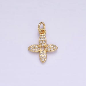 May include: A gold-tone pendant charm featuring a four-leaf clover design with clear cubic zirconia stones.