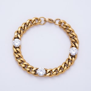 May include: Gold-toned curb chain bracelet with three round, clear, sparkling gemstones. The bracelet features a classic, chunky link design and a secure clasp. A stylish piece of jewelry.