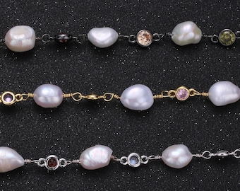 May include: Close-up of three strands of necklaces featuring irregularly shaped white pearls and small, colorful gemstones. The necklaces have gold, silver, and black metal chains. The background is a dark, speckled surface.