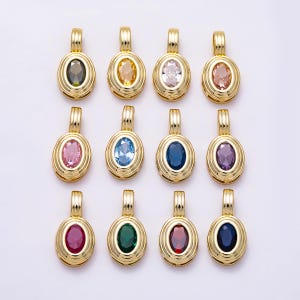 May include: Twelve oval-shaped gold-toned metal pendants, each featuring a central faceted gemstone in a different color including black, yellow, clear, peach, pink, light blue, dark blue, purple, magenta, green, red, and navy blue.