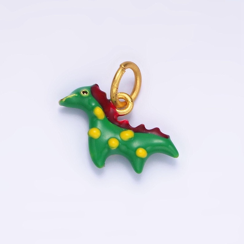 May include: A green dinosaur charm with yellow spots and a red crest. The charm has a gold loop for attaching to a necklace or bracelet.