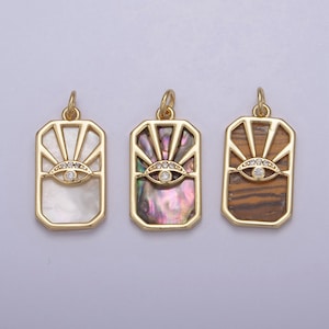 May include: Three gold pendant charms with an evil eye design. The charms are rectangular and feature a sunburst pattern. The center charm has a mother of pearl background, the left charm has a white background, and the right charm has a brown and gold background.