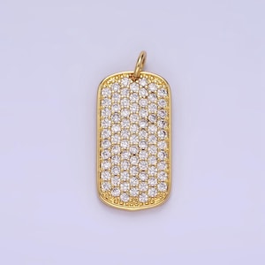 May include: A gold-toned pendant in the shape of a rectangular dog tag, completely covered in small, clear cubic zirconia stones.