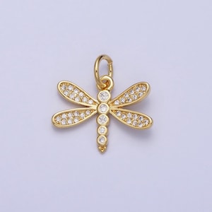 May include: Gold-toned dragonfly charm with clear crystal accents. The charm has a loop at the top for attaching to a necklace or bracelet.