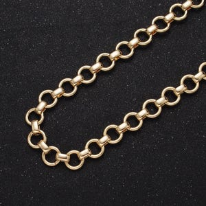 Puede incluir: Un collar de cadena de oro con un diseño de eslabón redondo. La cadena está sobre un fondo negro.