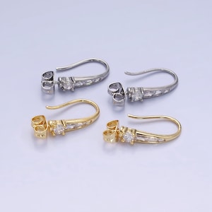 May include: Two pairs of gold and silver earring hooks with clear cubic zirconia stones. The hooks are adorned with a row of smaller clear stones.