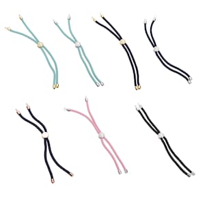May include: A collection of adjustable bracelets in various colors, including teal, black, and pink. Each bracelet features a central decorative element and cord ends in gold or silver tones. The bracelets are designed with a sliding knot for adjustability.