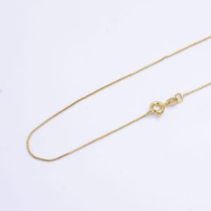 May include: A gold chain necklace with a box clasp. The chain is thin and delicate.