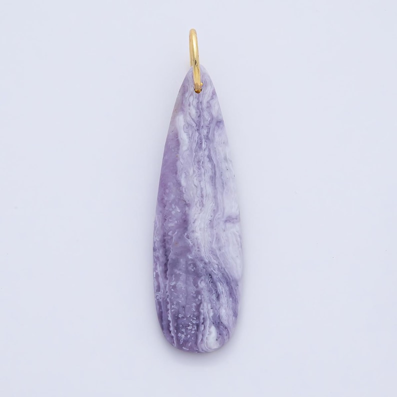 May include: A teardrop-shaped pendant with a marbled purple and white pattern. The pendant has a gold-colored loop at the top for hanging. The stone-like pendant is a unique accessory.
