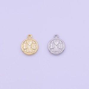 May include: Two round charms, one gold-colored and one silver-colored, each featuring a four-leaf clover design within a circular frame. Both charms have a small loop at the top for attaching to jewelry.