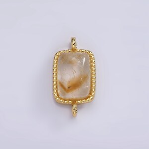 May include: Gold-toned pendant with a clear, rectangular quartz stone set in a beaded frame.