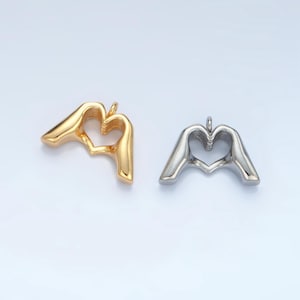 May include: Two pendants in the shape of hands forming a heart. One pendant is gold and the other is silver.