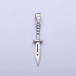 May include: A silver pendant in the shape of a dagger with a detailed handle and a sharp point.
