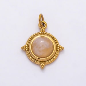 May include: Gold-coloured pendant featuring a round, pale stone centre. The pendant has a circular frame with a beaded edge and four decorative points. A small loop is at the top for a chain.