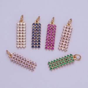 Puede incluir: Surtido de colgantes de charms de tono dorado con acentos de cristal de colores. Los charms son rectangulares y presentan un patrón repetitivo de pequeñas piedras facetadas. Los colores incluyen transparente, rosa, azul, verde y morado.