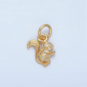 May include: A gold-toned squirrel charm with clear crystal accents. The charm has a loop at the top for attaching to a necklace or bracelet.