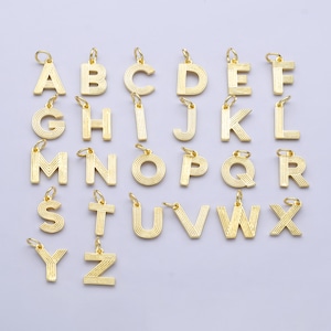 May include: A collection of gold-colored alphabet charms, each with a small loop at the top for attaching to a chain or bracelet. The letters A through Z are displayed, each with a grooved design.
