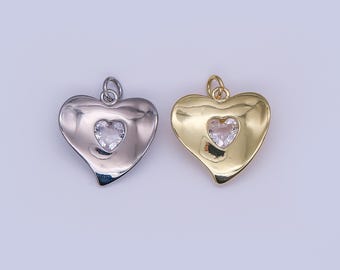 Puede incluir: Dos colgantes en forma de corazón. Uno es plateado, el otro dorado. Cada colgante tiene una piedra transparente más pequeña en forma de corazón en el centro. Ambos colgantes tienen un lazo en la parte superior para sujetarlos a una cadena u otra joya.