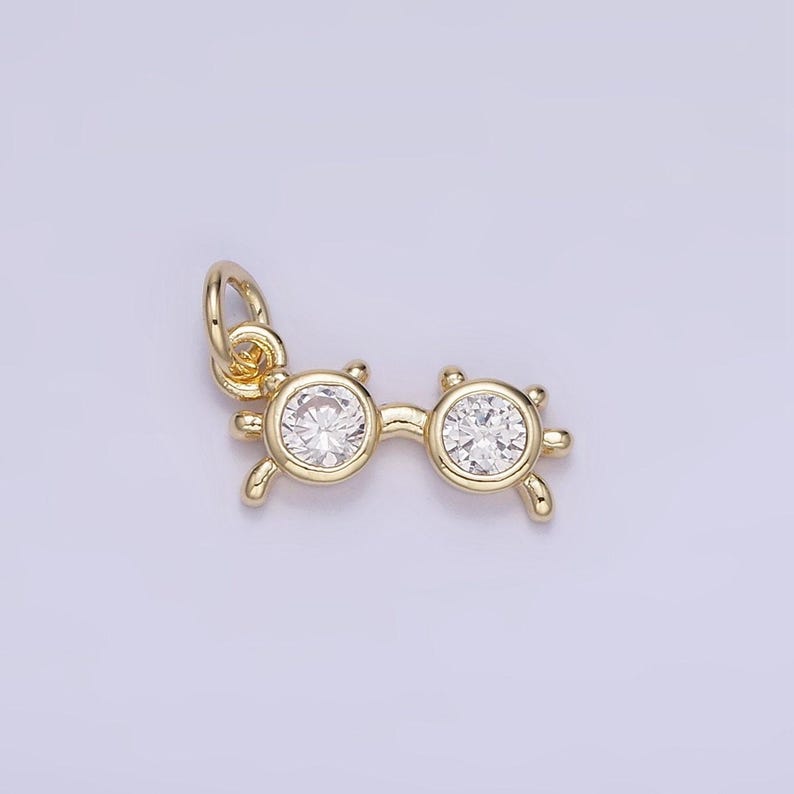 May include: Gold-tone charm in the shape of eyeglasses with clear crystal accents.