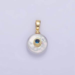 May include: A white pearl pendant with a gold setting and a small blue gemstone in the center.