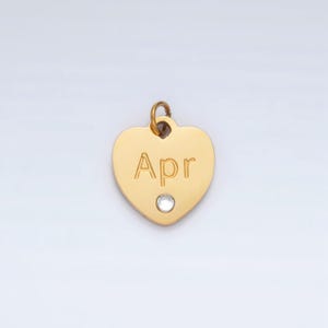 May include: Gold heart-shaped charm with a clear rhinestone and the word "Apr" engraved on it.