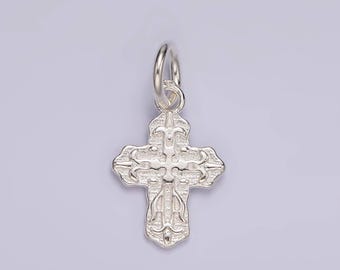 May include: A silver charm in the shape of a cross with intricate details. The cross has a loop at the top for attaching to a chain or bracelet.