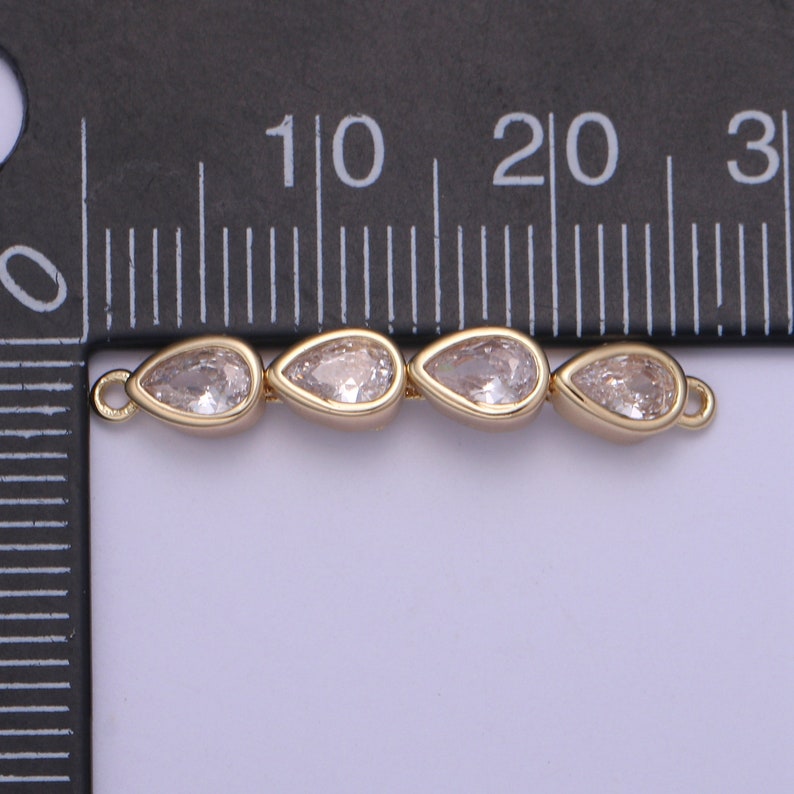 Puede incluir: Un conector dorado con tres cristales transparentes en forma de l&aacute;grima. El conector mide aproximadamente 2 cm de largo.