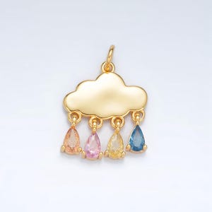 Puede incluir: Un colgante de nube dorada con cuatro gemas en forma de lágrima en naranja, rosa, amarillo y azul. El colgante tiene un lazo para sujetarlo a una cadena. El colgante está diseñado para joyería.