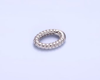 May include: A silver oval-shaped ring with a twisted rope design.