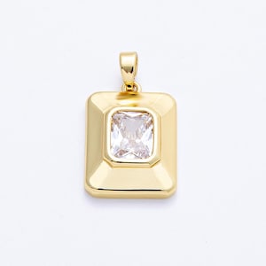 May include: Gold-toned pendant with a rectangular shape. The pendant features a clear, rectangular gemstone set in the center. The bail is integrated into the design. The pendant is displayed against a white background.