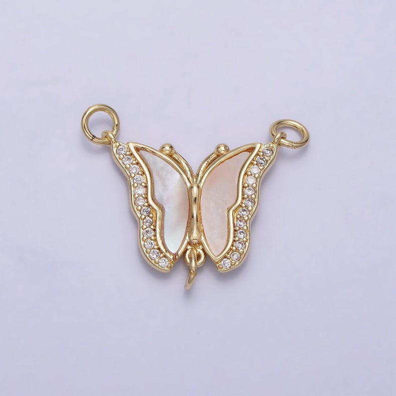 May include: Gold butterfly charm with a white mother of pearl inlay and clear crystal accents.