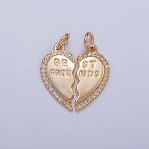 May include: Two gold-tone best friend charms in the shape of broken hearts with clear rhinestones around the edges. The charms say "BEST FRIENDS" on them.