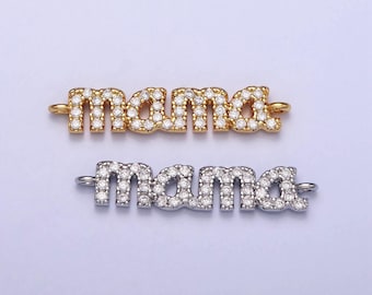 Puede incluir: Dos colgantes con la palabra "mama", uno dorado y otro plateado, ambos incrustados con pequeños cristales transparentes. Cada colgante tiene bucles en cada extremo para sujetarlo a la joyería. Los colgantes se muestran sobre un fondo lila claro.
