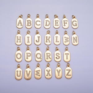 May include: A set of 26 gold-toned charms, each featuring a letter of the alphabet, adorned with clear sparkling rhinestones. The charms are shaped like small rectangular pendants.