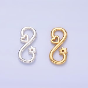 Puede incluir: Dos abalorios con símbolo de infinito, uno plateado y otro dorado. Ambos abalorios tienen un pequeño corazón y una estrella en el centro.