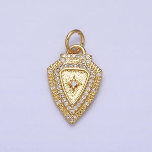 May include: Gold pendant charm with a diamond-shaped design. The pendant features a small star with a clear stone in the center, surrounded by a border of smaller clear stones.