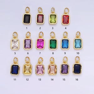 May include: Assortment of 16 gold-tone charms with different colored glass stones. Each charm features a rectangular shape with a gold-tone bail.