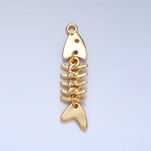 May include: Gold-toned fish bone charm with a detailed design. The charm is made of metal and has a loop at the top for attaching to jewelry or other crafts.