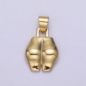 Op de afbeelding: Een goudkleurige hanger met een unieke vorm, met een lus aan de bovenkant voor een ketting. De hanger heeft een glad, reflecterend oppervlak en een onderscheidend, abstract ontwerp. De algehele esthetiek is modern en minimalistisch.