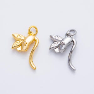 May include: Two dragonfly pendants, one gold-toned and one silver-toned, each with a small gemstone. The pendants feature leaf-shaped wings and a curved body, designed for jewelry making or as decorative charms.