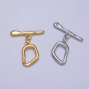 May include: Two metal toggle clasps with a dangling, irregular shaped loop. One clasp is gold and the other is silver.