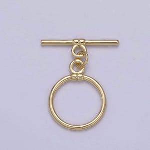 May include: Gold-toned metal toggle clasp with a round ring. The clasp has a bar with two round knobs on each end and a double loop chain attached to the bar.