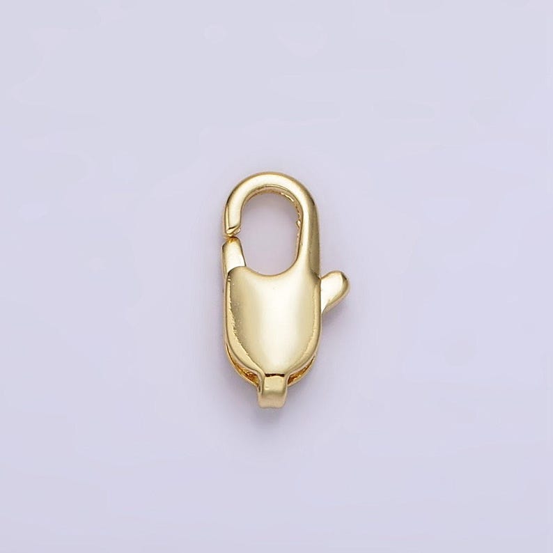 May include: Gold-toned metal lobster clasp for jewelry making. The clasp is a simple, oval-shaped design with a spring-loaded mechanism.