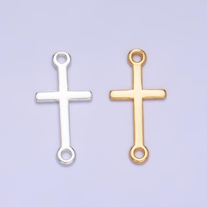 May include: Two metal cross charms, one silver and one gold, with a loop at the top and bottom for attaching to jewelry.