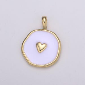 Puede incluir: Colgante de oro con un círculo de esmalte blanco y un pequeño corazón de oro en el centro.