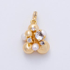 May include: A gold-toned pendant featuring a cluster of pearls and crystals. The design includes large, round, gold-colored beads, interspersed with white pearls and clear, sparkling crystals. The pendant has a small loop for attaching to a chain.